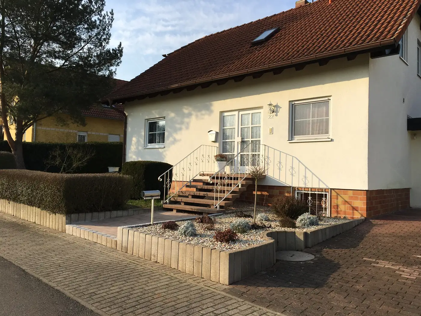 Gepflegter Vorgarten mit geschnittener Hecke, Kiesbeet und sauberer Zuwegung