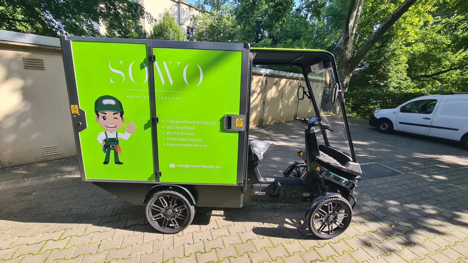Ladebox des E-Lastenrads mit SoWo-Logo und den Leistungen Treppenhausreinigung, Gartenpflege, Winterdienst, Kleinreparaturen und Hausmeisterservice