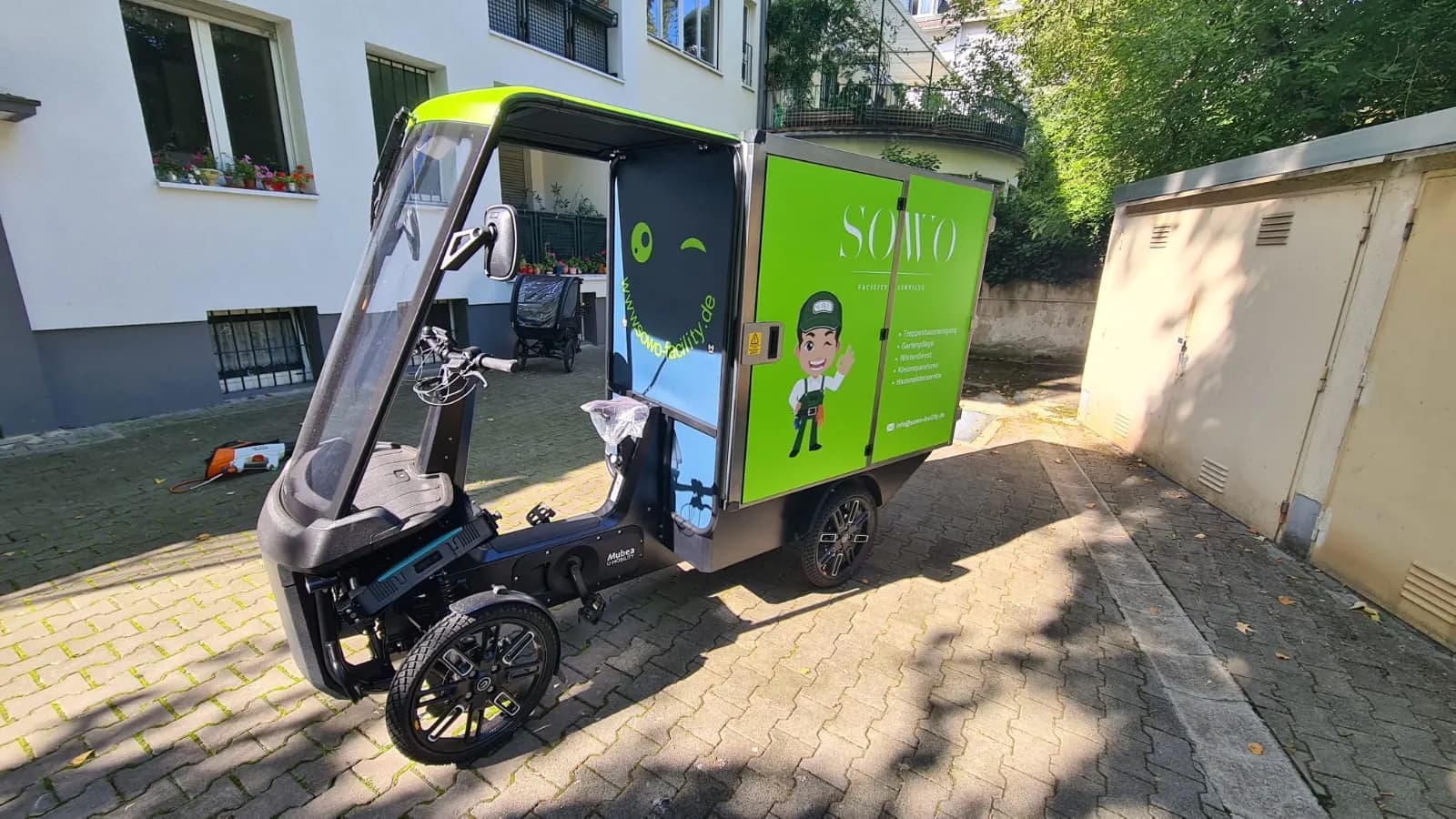 E-Lastenrad mit geöffneter Ladebox im Hinterhof eines Frankfurter Mehrfamilienhauses