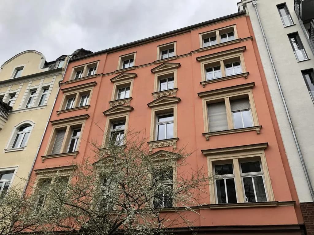 Altbaufassade in warmem Rotton mit blühendem Baum in Frankfurt-Bockenheim
